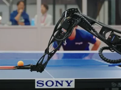 robotic-arm-with-paddle-and-an-orange-ping-pong-ball-hovering-over-a-sony-labeled-table-tennis-table